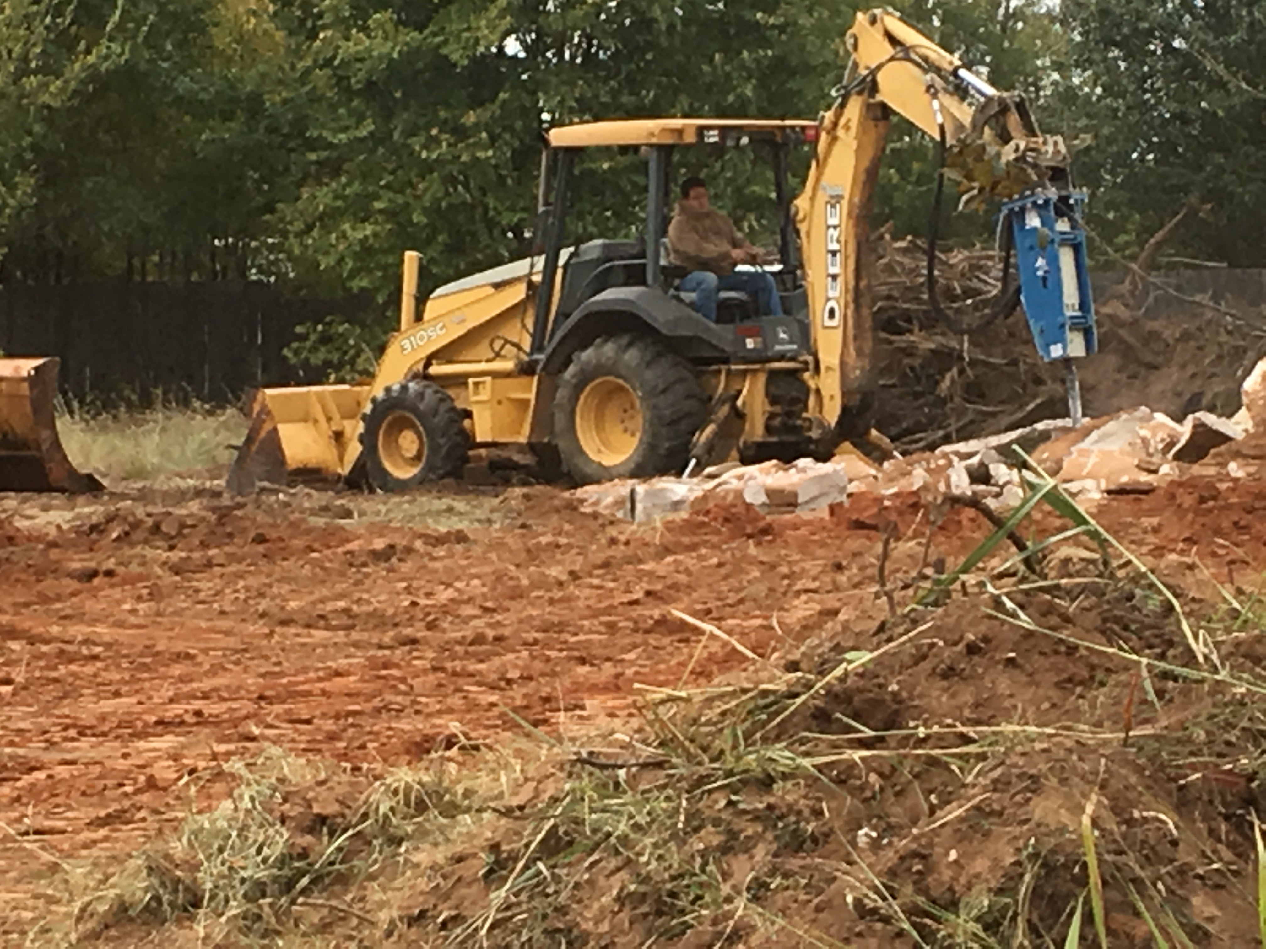 Scott Construction & Excavation operator running a backhoe while clearing land near Granbury, TX