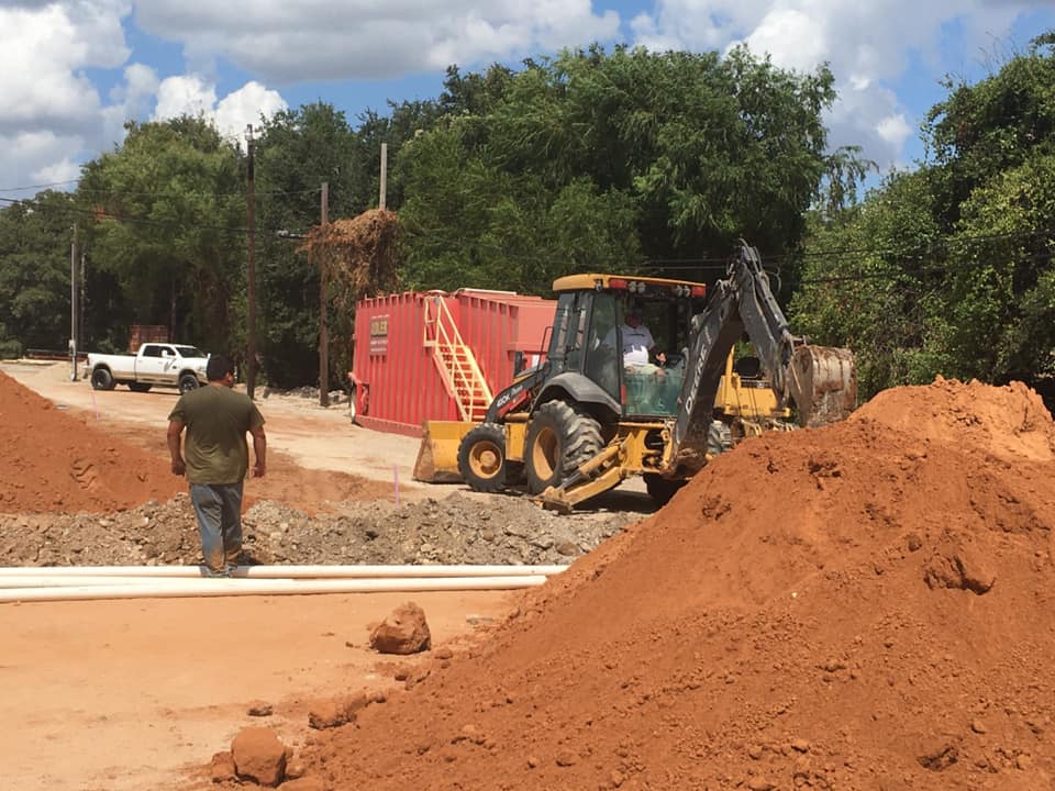 Backhoe and crew clearing and grading a job site near Granbury, Texas