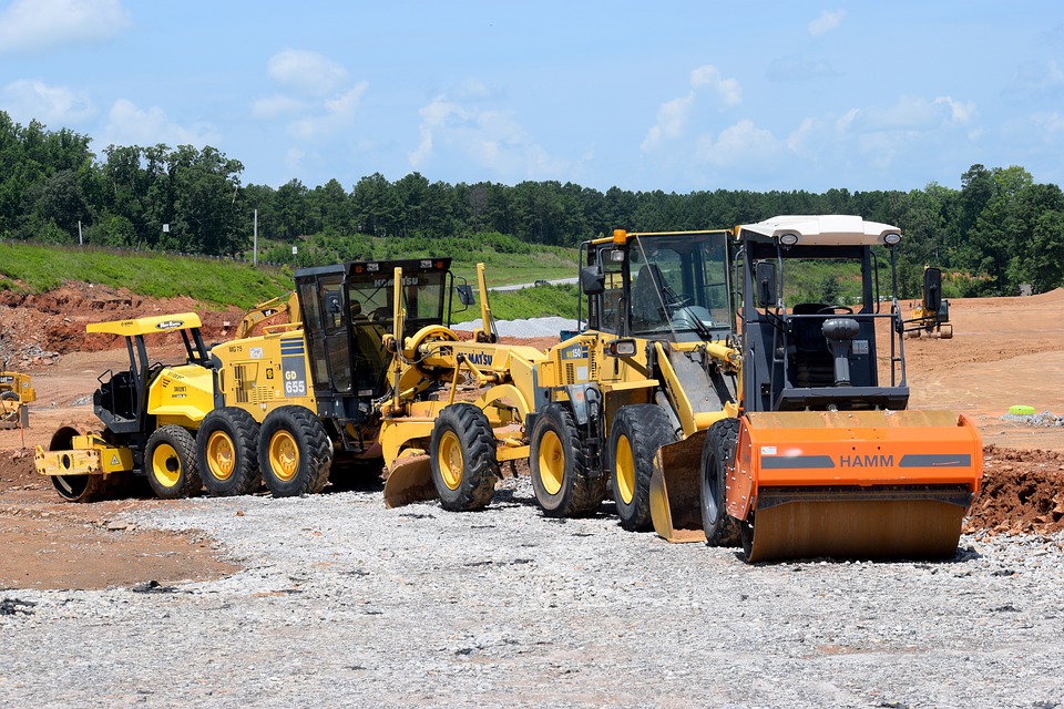 Grader and roller compacting road base material for a driveway access project